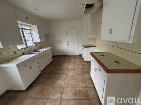 A kitchen with white cabinets and a tiled floor.