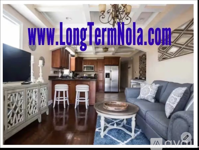 A living room with a couch, a coffee table, and a kitchen area in the background.