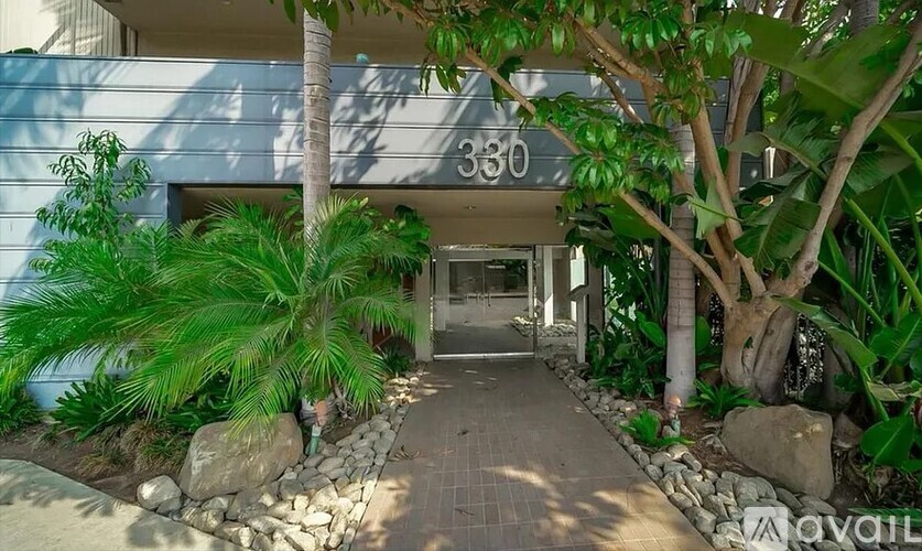 A building entrance with a stone pathway and green plants on either side.