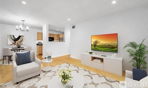 A living room with a white sofa, a coffee table, a TV, and a plant.