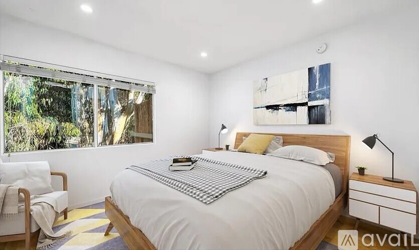 A bedroom with a large bed, a chair, and a painting on the wall.