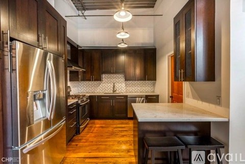 A kitchen with dark wood cabinets and a stainless steel refrigerator.