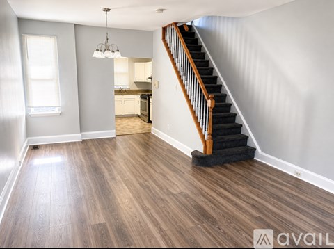 A wooden staircase with a black carpeted stair runner leads up to a kitchen area.