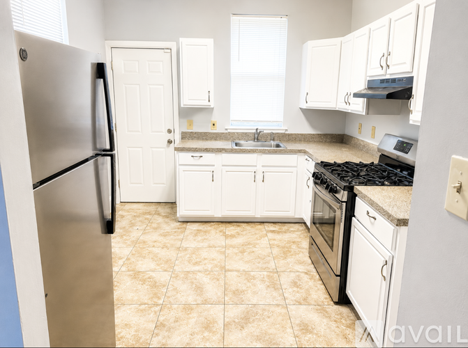 A kitchen with a refrigerator, oven, and sink.