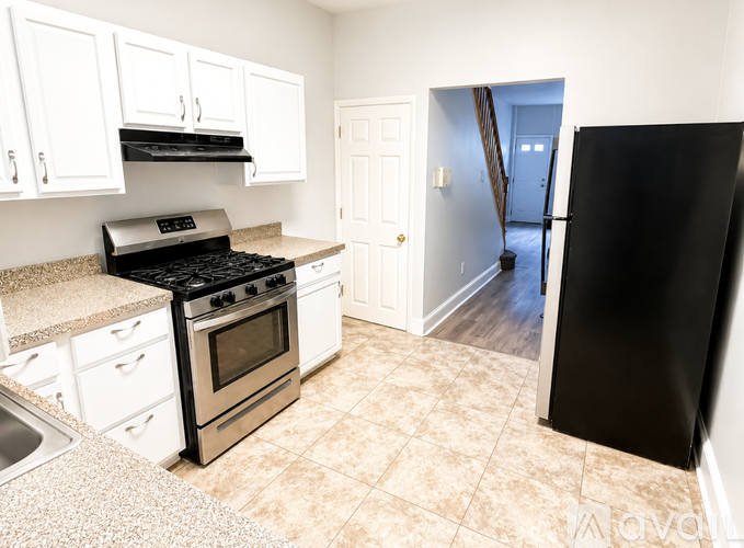 A kitchen with white cabinets and a black fridge.
