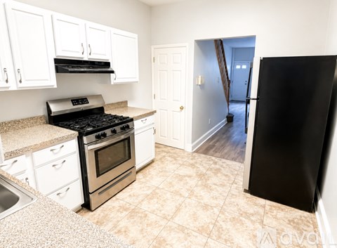 A kitchen with white cabinets and a black fridge.