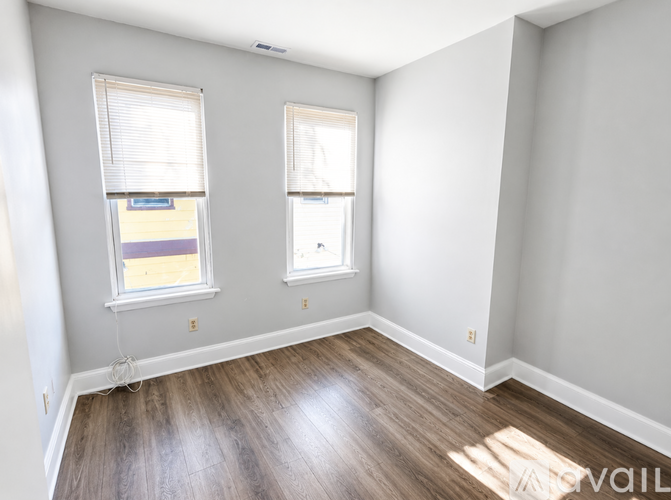 A room with two windows and wooden flooring.