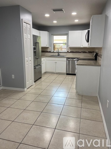 A kitchen with white cabinets and a tile floor.