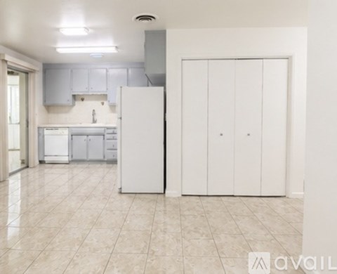 A kitchen with a white refrigerator and cabinets.
