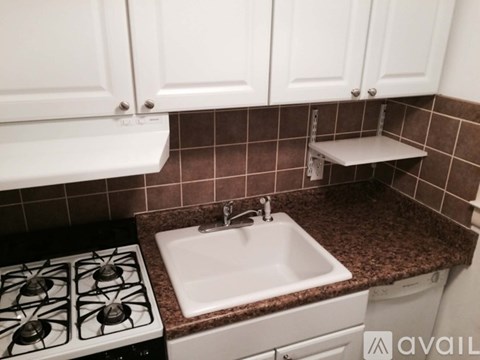 A kitchen with a white stove, sink, and cabinets.