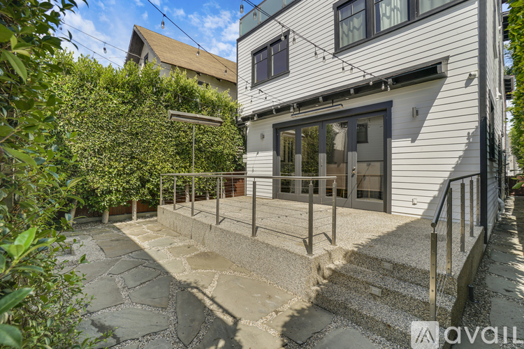 A modern house with a stone patio and stairs leading to the entrance.