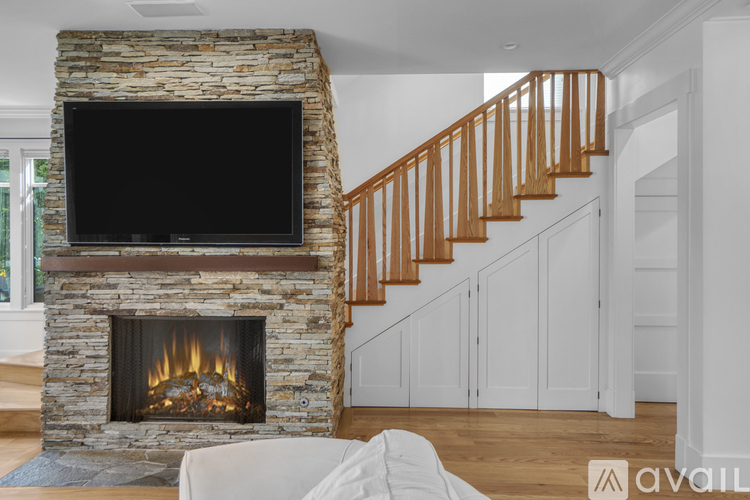 A living room with a stone fireplace and a television mounted above it.