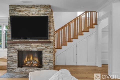 A living room with a stone fireplace and a television mounted above it.