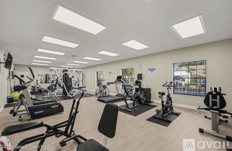 A well-lit gym with various exercise equipment and a view of the outside.