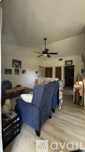 A living room with a blue chair and a ceiling fan.