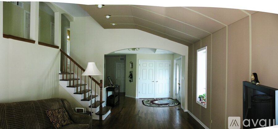 A living room with a couch, a fireplace, and a staircase.