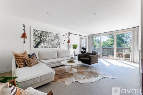 A living room with a white couch, a brown rug, and a painting on the wall.
