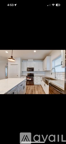 A modern kitchen with white cabinets and a wooden floor.