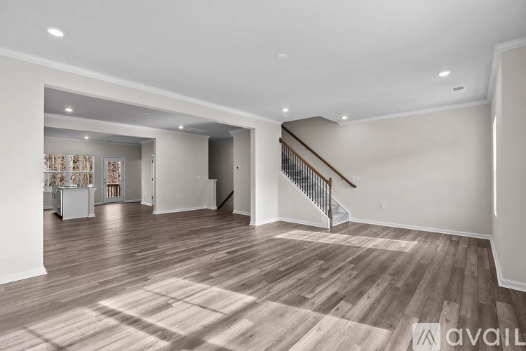 A spacious living room with wooden flooring and a staircase.