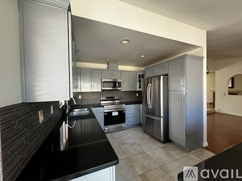 A modern kitchen with stainless steel appliances and a black countertop.