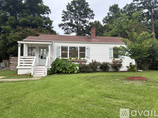 A small white house with a red roof and a porch.