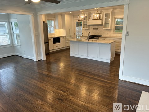 A kitchen with white cabinets and a wooden floor.