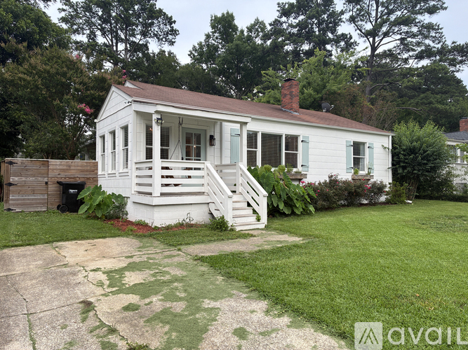 A white house with a brown roof and a porch.