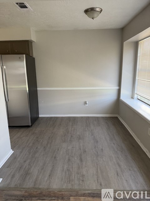 A kitchen with a stainless steel refrigerator and wooden flooring.