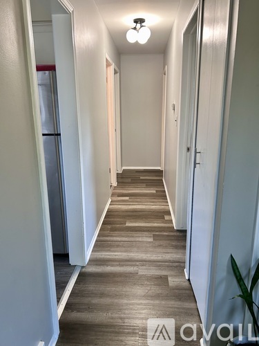 A long hallway with wood floors and white walls.