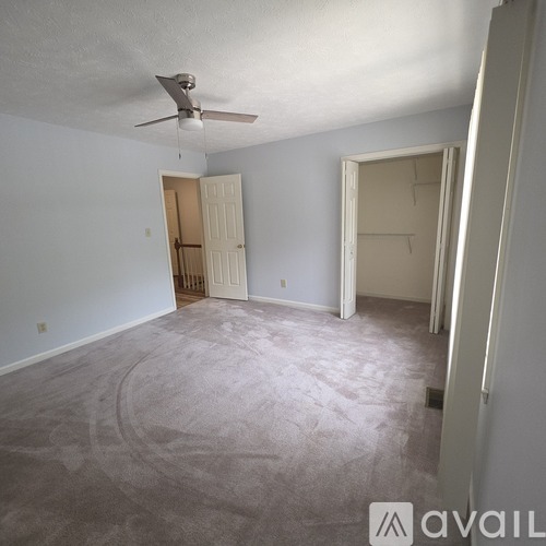 A room with a ceiling fan and two open doors.