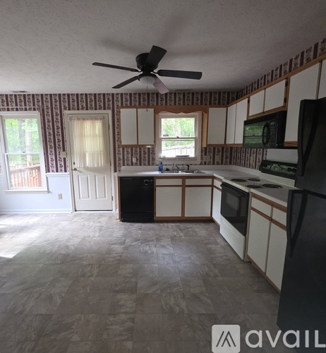 A kitchen with a black fridge and a black fan.