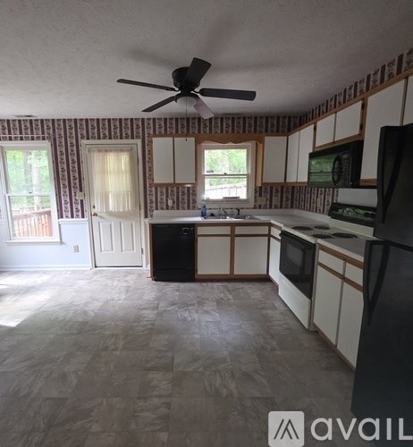 A kitchen with a black fridge and a black fan.