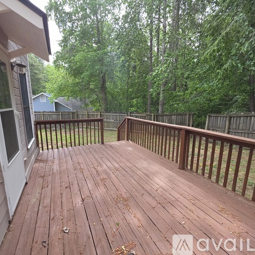 A wooden deck with a railing and trees in the background.