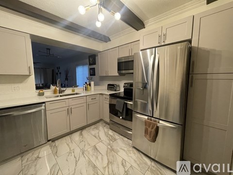 A modern kitchen with a stainless steel refrigerator and marble countertops.