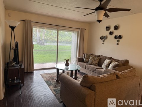 A living room with a couch, a coffee table, and a ceiling fan.