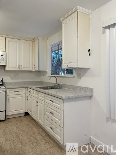 A kitchen with white cabinets and a window.