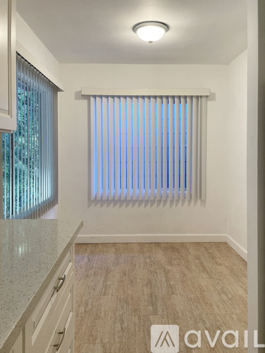 A kitchen with a counter top and a window with blinds.