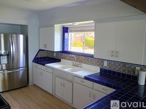 A kitchen with white cabinets and a blue tile backsplash.