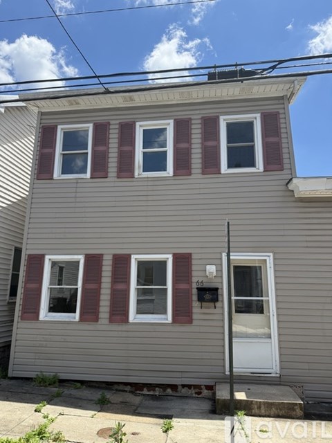 A house with a grey siding and red shutters.