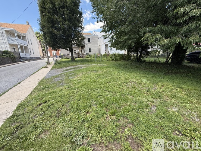A grassy area with a road and houses in the background.