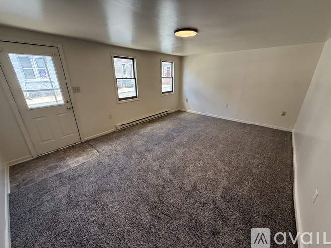 A room with a carpeted floor and three windows.
