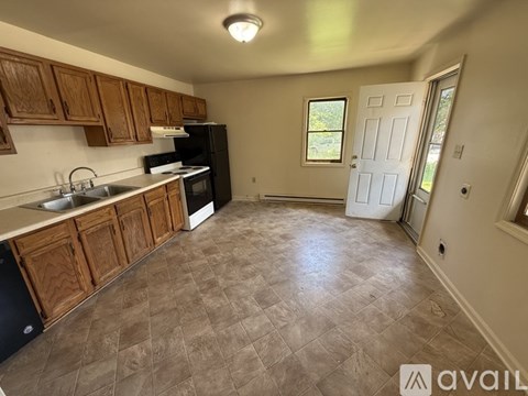 A kitchen with wooden cabinets and a black refrigerator.