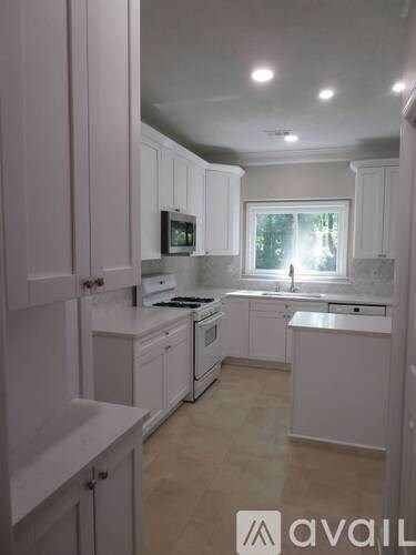 A kitchen with white cabinets and a window.