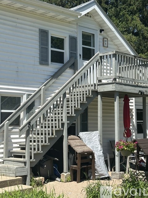 A white house with a grey staircase and a red umbrella.