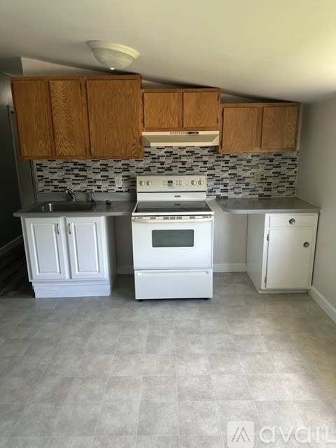 A kitchen with a white stove top oven and white cabinets.