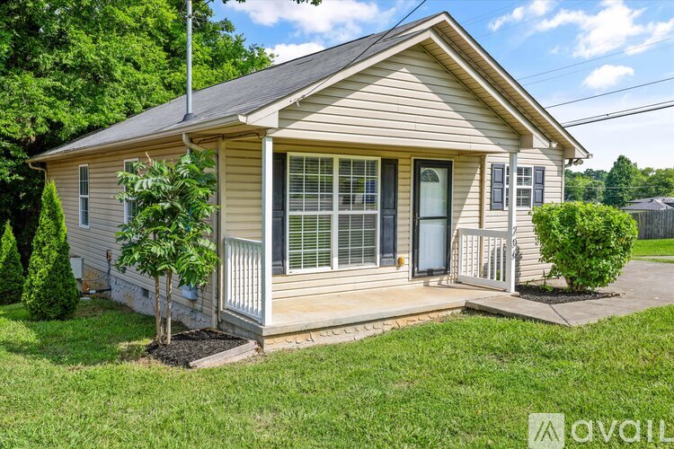 A small house with a front porch and a tree in front of it.