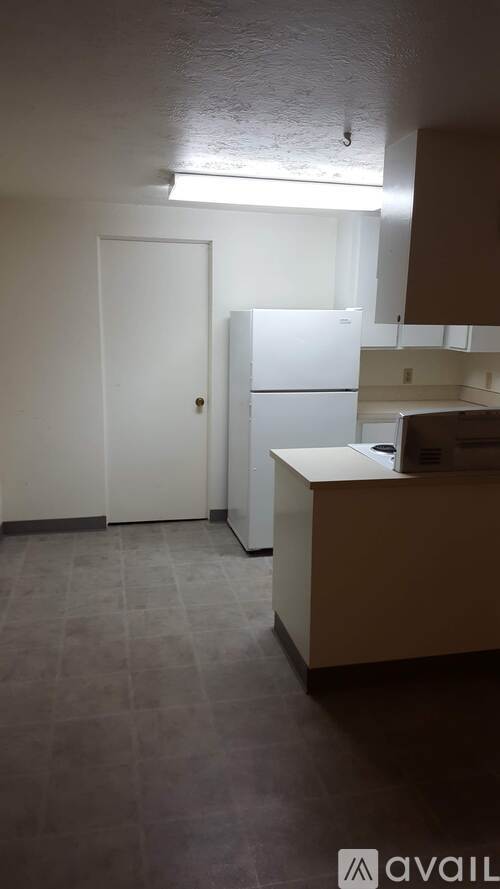 A kitchen with a white door and a white fridge.