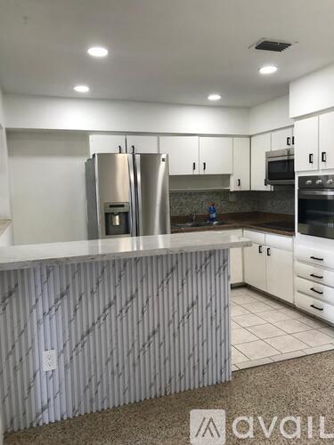 A kitchen with a white counter top and stainless steel appliances.