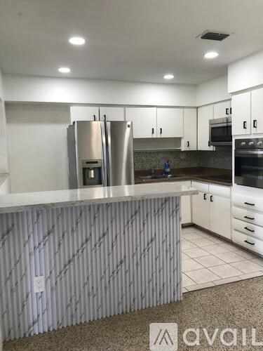 A kitchen with a white counter top and stainless steel appliances.
