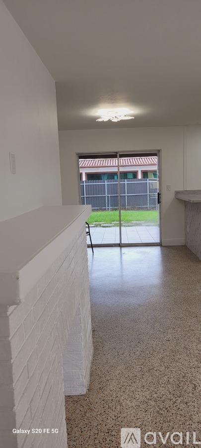 A room with a white ceiling and a window with a view of a fence and a building.